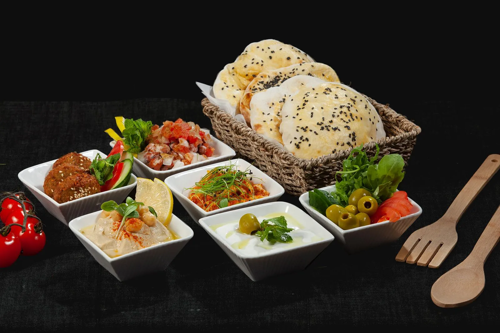 A variety of Middle Eastern dishes with fresh pita bread in a woven basket, perfect for sharing.